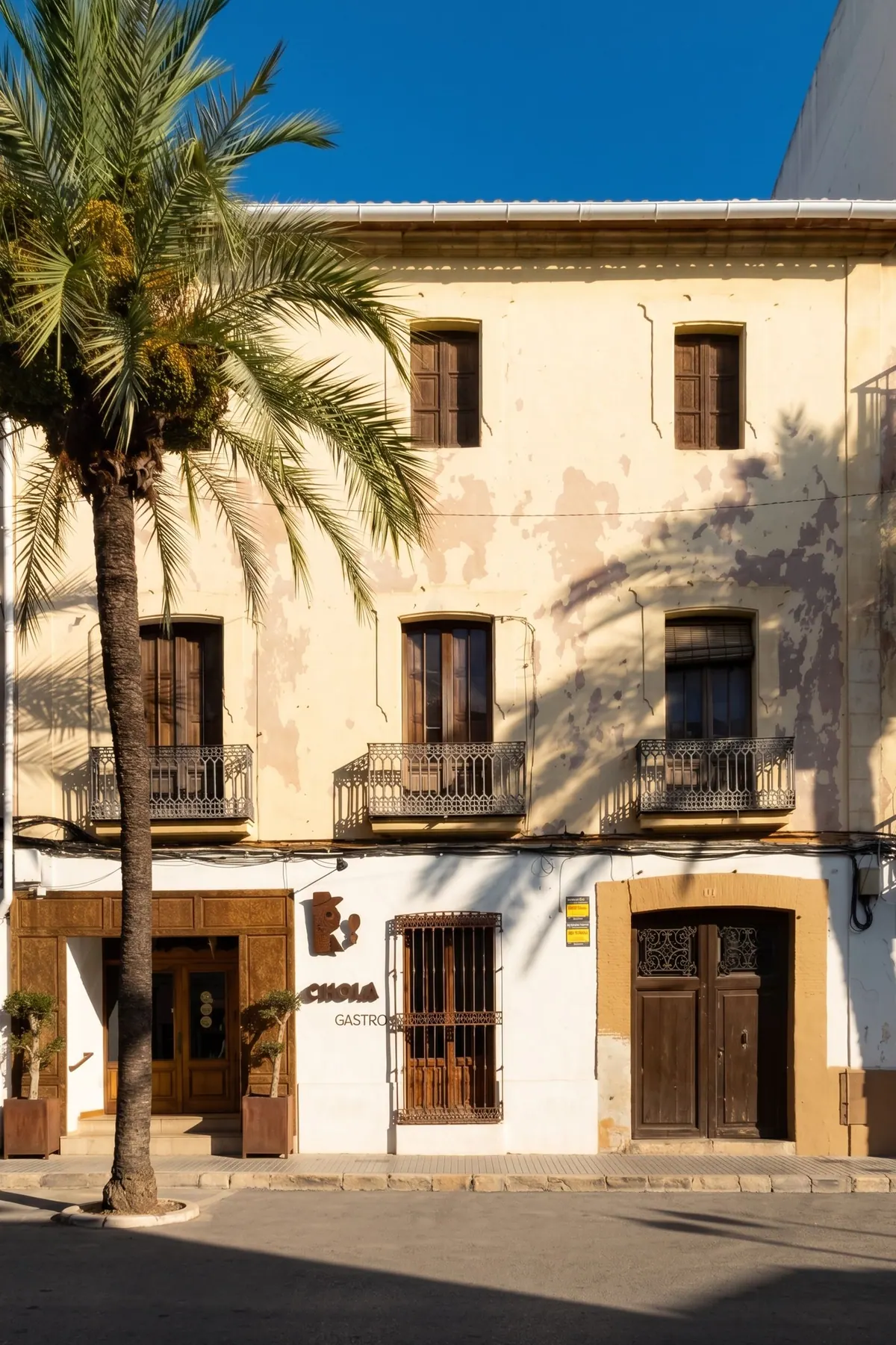 Heritage Jávea — the facade of a historic town house with balconies and a palm tree, current state