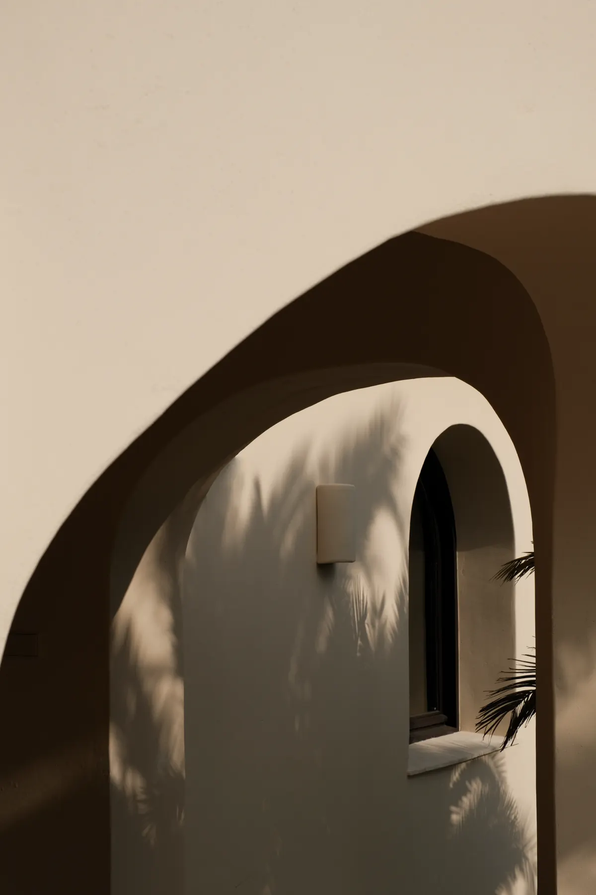 An arched opening and wall light on a curved lime wall