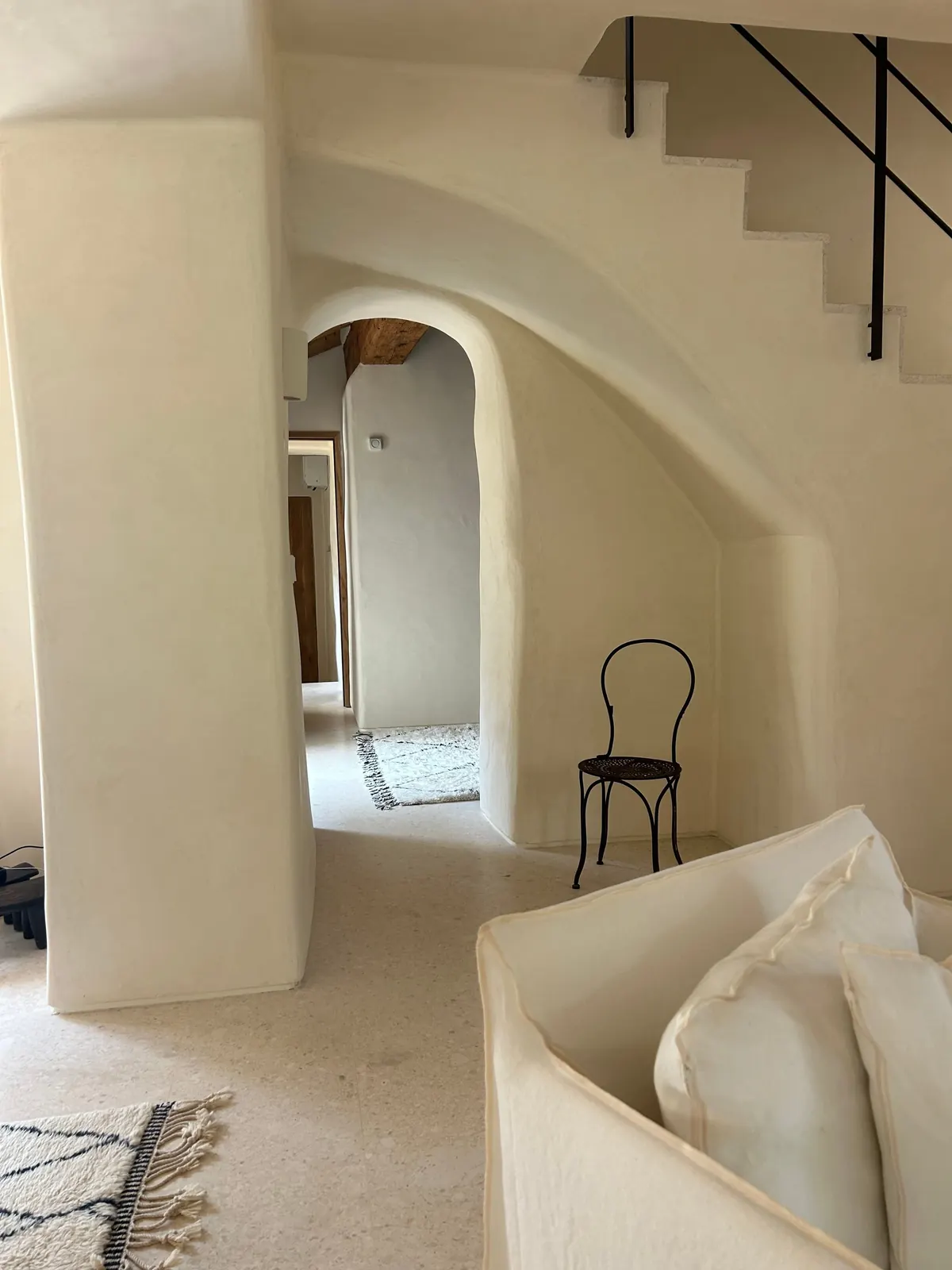 Whitewashed arches and a bentwood chair in a soft white interior