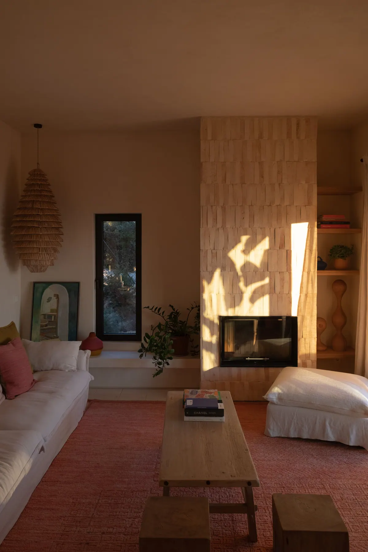 A living room with a tiled fireplace wall, low timber table and red rug
