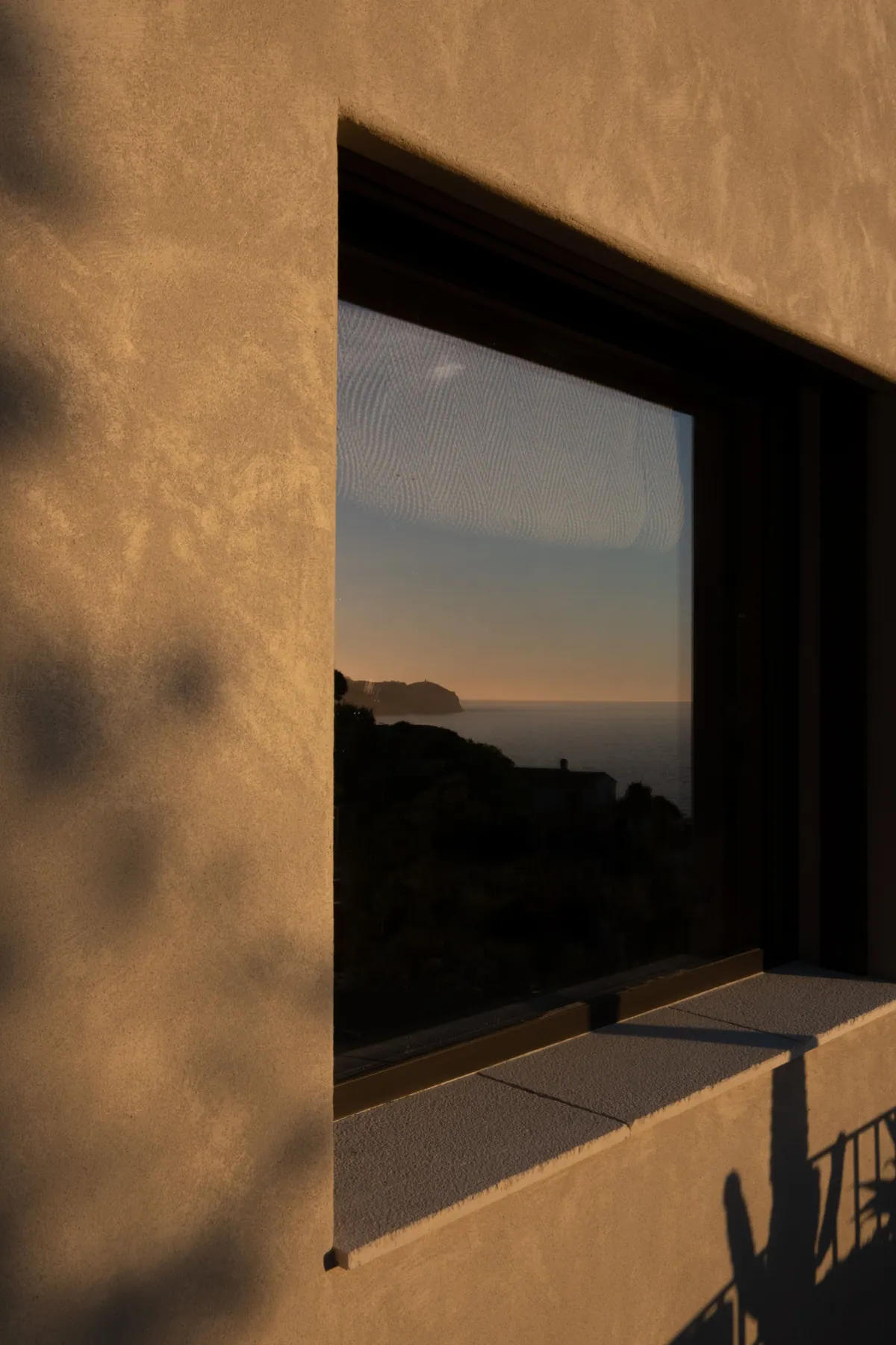 A deep-set window reflecting the coastline at dusk