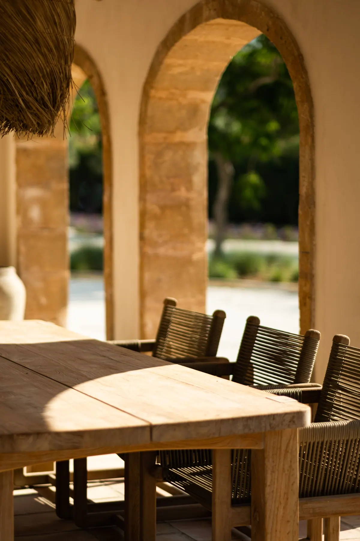 Stone arches framing a dining table and woven chairs