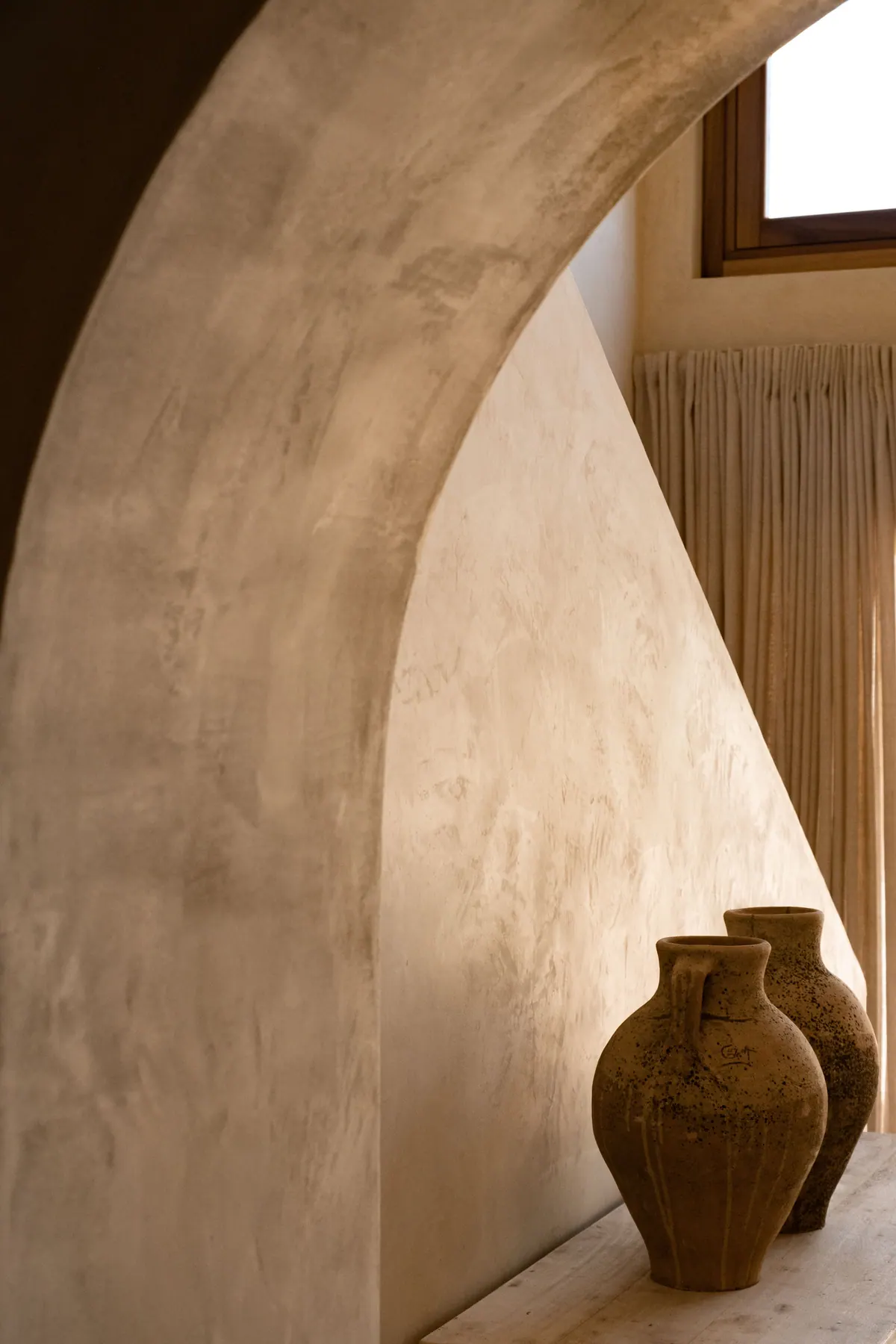 A soft lime arch and two terracotta jars in warm light