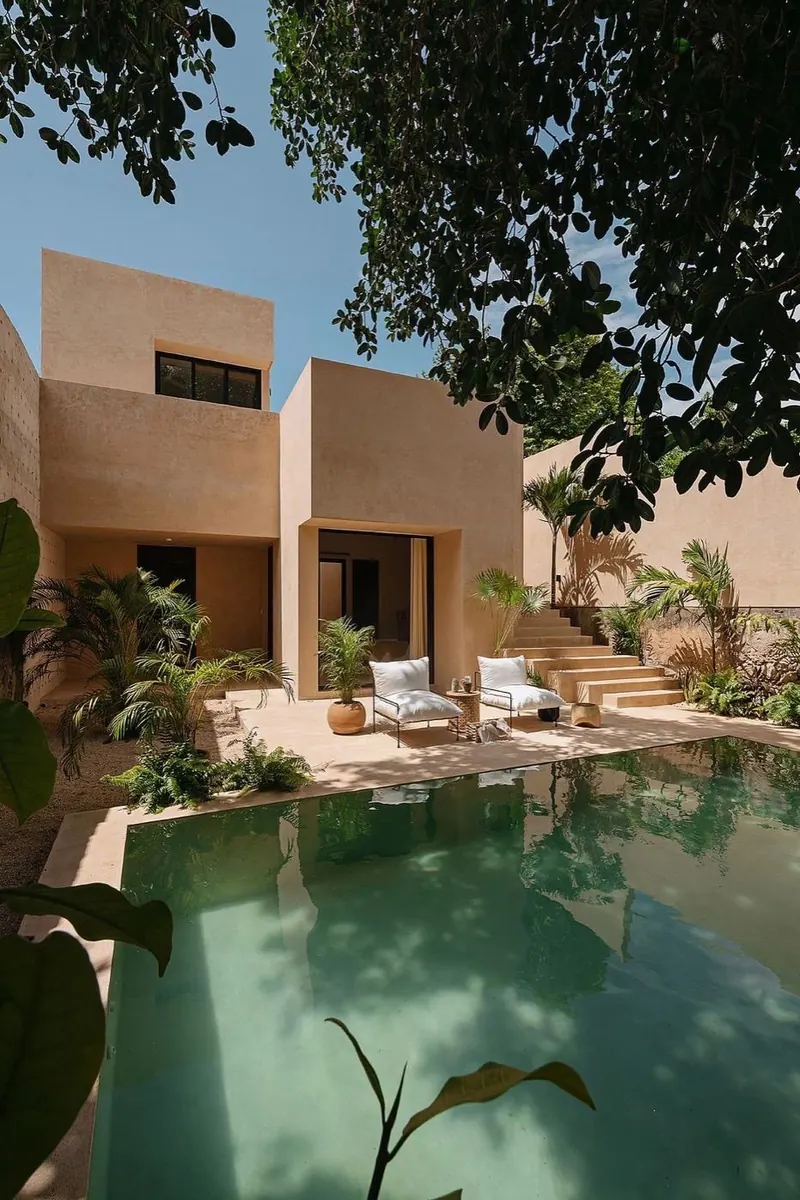 Mood image: a pool courtyard between earth-toned volumes and trees