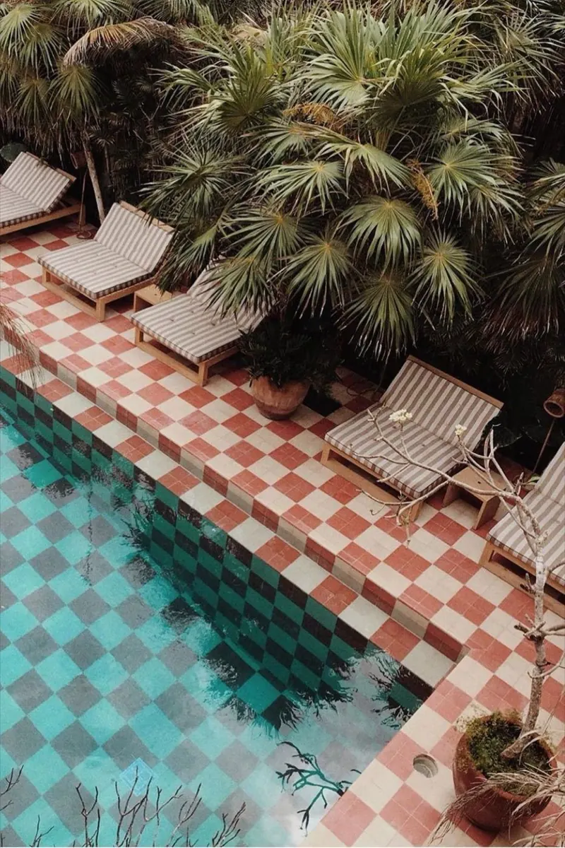 Mood image: striped loungers beside a chequered pool under palms