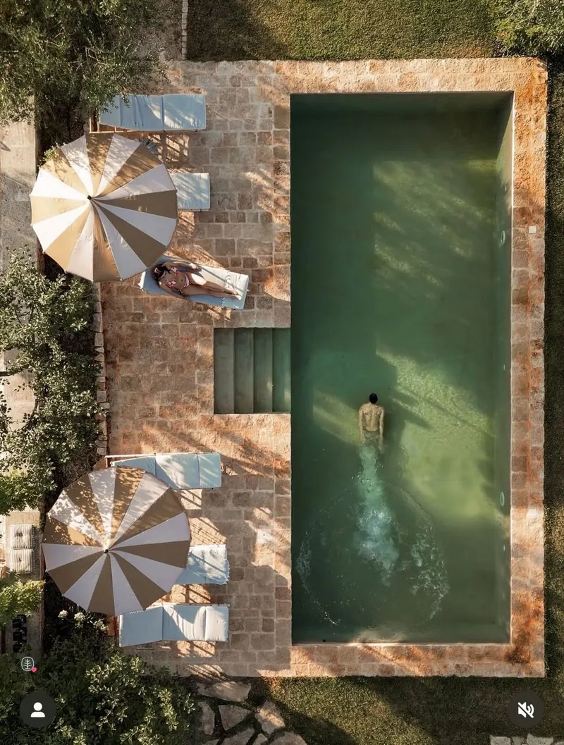 Mood image: a green pool seen from above, with striped parasols